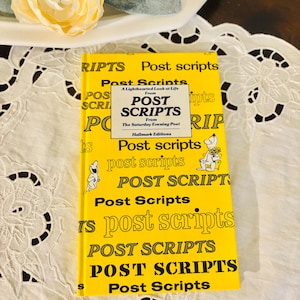 May include: A yellow book titled "Post Scripts" with the text repeated across the cover. The book is from The Saturday Evening Post, Hallmark Editions. A light yellow flower and green leaves are in the background.