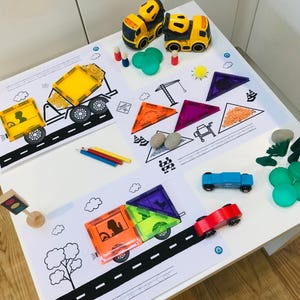 May include: A selection of children's construction toys and educational resources. Features yellow toy trucks, magnetic tiles, colouring pages with road and construction designs, and coloured pencils. A playful and educational set for young children.