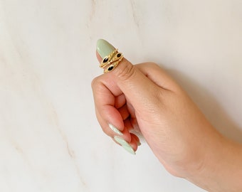May include: Three gold rings with black oval stones set in a delicate design. The rings are stacked on a finger.