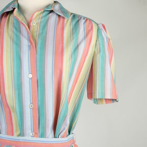 May include: A striped dress with a button-up front and short sleeves. The dress is made of a light fabric and has a variety of colors, including pink, blue, green, and yellow.