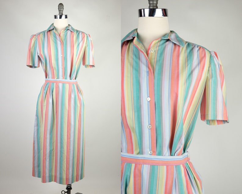 May include: A striped dress with a button-up front and short sleeves. The dress has a light blue, pink, green, and yellow striped pattern. The dress has a belt.
