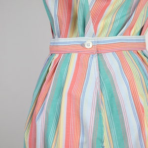 May include: A striped dress with a button closure at the waist. The dress is made of a lightweight fabric and features a variety of colors, including pink, green, yellow, and blue.