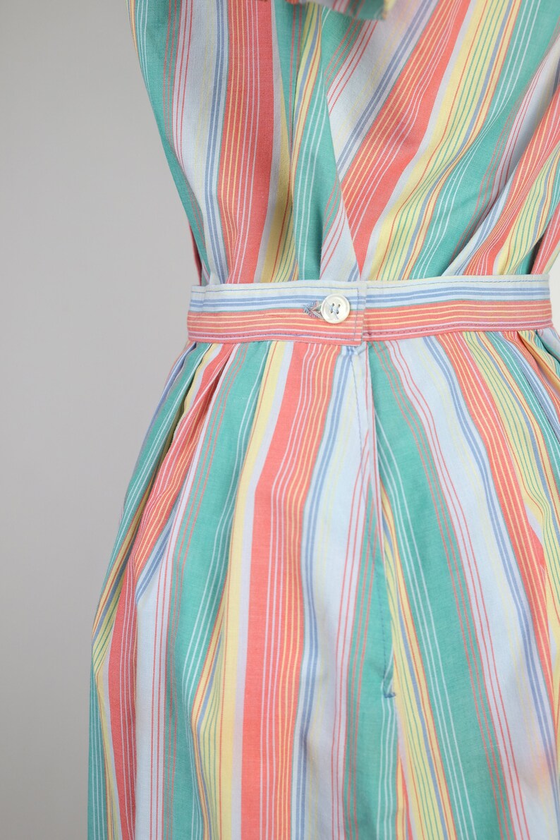 May include: A striped dress with a button closure at the waist. The dress is made of a lightweight fabric and features a variety of colors, including pink, green, yellow, and blue.