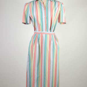 May include: A striped dress with a button-up front and short sleeves. The dress is a mix of pastel colors, including pink, blue, yellow, and green.