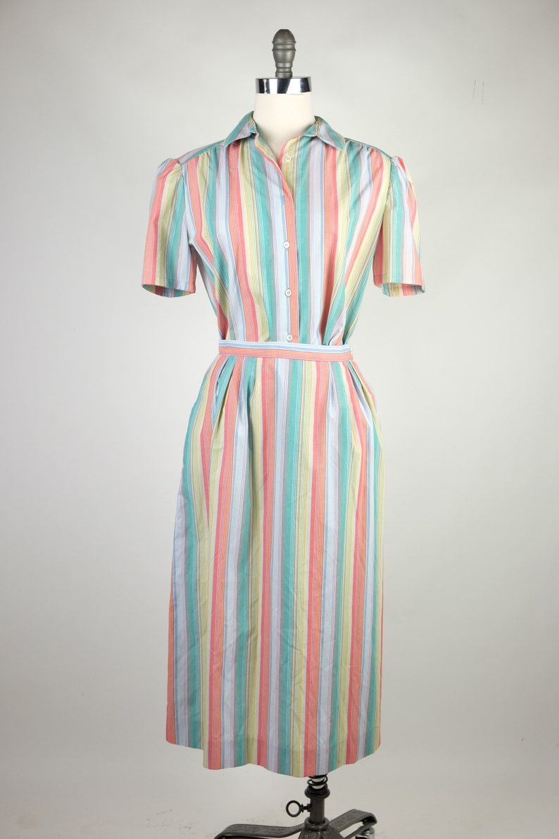 May include: A striped dress with a button-up front and short sleeves. The dress is a mix of pastel colors, including pink, blue, yellow, and green.