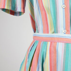 May include: A striped dress with a blue, green, yellow, and pink color scheme. The dress has a button-up front and a gathered skirt.