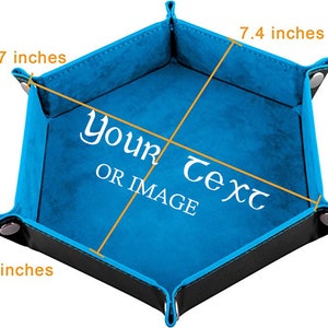 May include: A blue felt-lined dice tray with black leather edges. The tray is shaped like a hexagon and measures 18.8 cm across and 22.1 cm from corner to corner. The tray has a 4.1 cm tall side. The tray has the text "Your Text OR IMAGE" printed in white.
