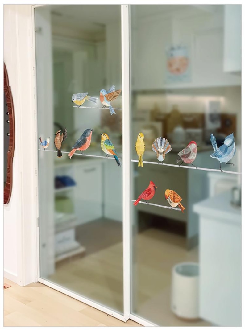 May include: A collection of colorful bird decals are affixed to a glass door. The birds are depicted in various poses and colors, including red, blue, yellow, and orange. The decals are arranged as if perched on a wire.