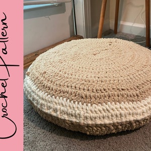 May include: A round crocheted cushion with a beige center and a white border. The cushion is sitting on a carpet.