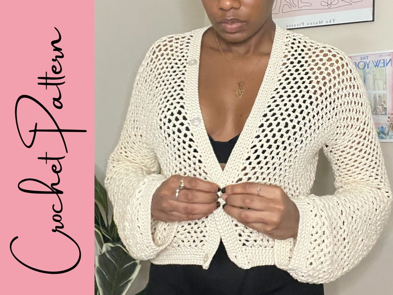 May include: A white crochet cardigan with a button closure and a loose fit. The cardigan has a delicate openwork pattern and long sleeves.
