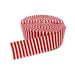 May include: A roll of red and white striped fabric ribbon. The ribbon is rolled up and the end is unfurled.