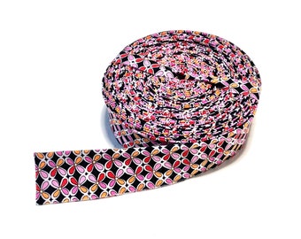 May include: A roll of black and white fabric with a pink, orange, and red floral pattern. The fabric is rolled up and tied with a ribbon.