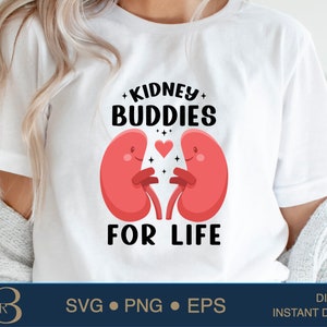 Puede incluir: Camiseta blanca con un diseño gráfico de dos riñones rojos que se toman de la mano con un corazón entre ellos. El texto "KIDNEY BUDDIES FOR LIFE" está impreso debajo de los riñones.