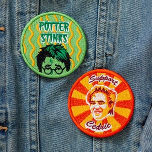 May include: Two embroidered patches on a denim jacket. One green patch reads "Potter Stinks" with a cartoon image. The other patch is orange and red with the text "Support Cedric" and a portrait.