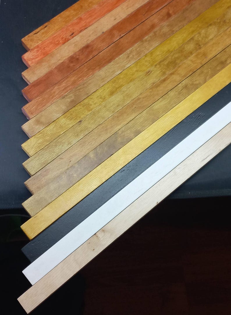 May include: A collection of wooden strips in various shades of brown, yellow, and orange, arranged in a diagonal pattern. The strips are painted in different colors, including black and white.