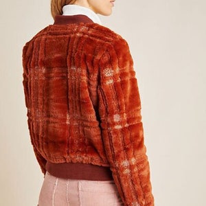 May include: A brown and white plaid faux fur bomber jacket with a ribbed knit collar and cuffs.