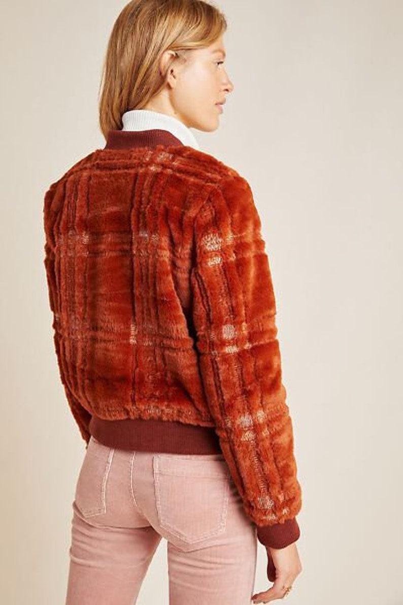May include: A brown and white plaid faux fur bomber jacket with a ribbed knit collar and cuffs.