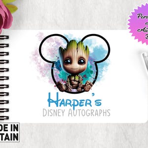 May include: A white A6 autograph book with a blue and green watercolor Mickey Mouse design featuring a character from the Guardians of the Galaxy movie. The text "Harper's Disney Autographs" is printed in blue below the design.