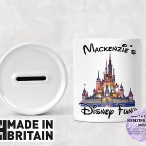 May include: White ceramic piggy bank with a slot on top. The front of the bank features a colorful illustration of Cinderella's castle from Disney World. The text "Mackenzie's Disney Fund" is printed below the castle.