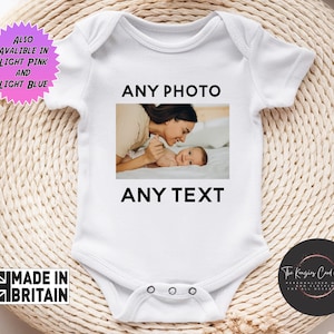 Puede incluir: Body de bebé blanco con el texto "ANY PHOTO" encima de una foto de una madre y un bebé, y "ANY TEXT" debajo. Un gráfico de estrella rosa y azul dice "TAMBIÉN DISPONIBLE EN ROSA CLARO Y AZUL CLARO". El body tiene un gráfico "MADE IN BRITAIN".