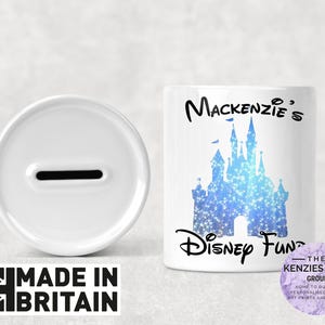 Può includere: Salvadanai in ceramica bianca con una fessura sulla parte superiore, accanto a un coperchio abbinato. La banca presenta un disegno di castello blu e le parole "Mackenzie's Disney Fund". Le parole "Made in Britain" sono stampate in basso a sinistra.