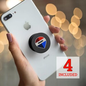 May include: A black phone grip with the RE/MAX logo in red, white, and blue is attached to a white iPhone. The phone is held in a hand. The image includes the text "4 INCLUDED".