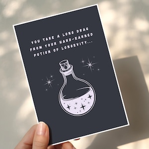 May include: A dark gray card with white text and a potion bottle illustration. The text reads "YOU TAKE A LONG DRAG FROM YOUR HARD-EARNED POTION OF LONGEVITY..." The bottle has stars inside and is surrounded by starbursts.