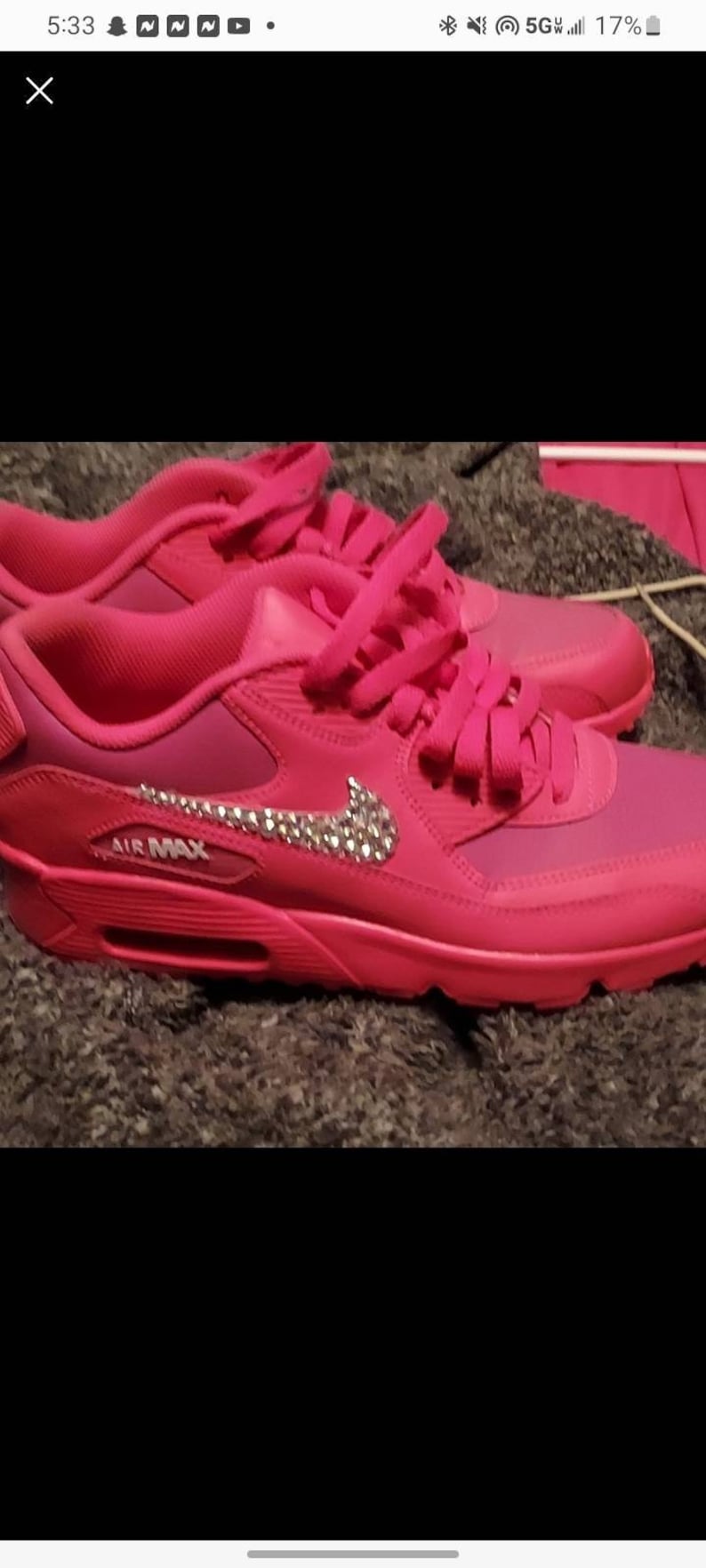 Pu&ograve; includere: Sneakers Nike Air Max rosa con un swoosh bianco e strass. Le scarpe hanno lacci rosa e un logo "AIR MAX" bianco sul lato.