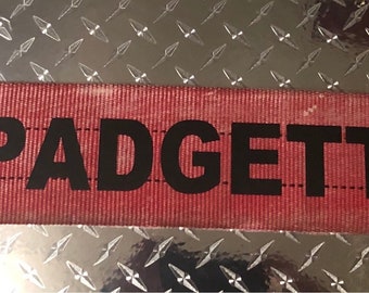 Czerwona tabliczka znamionowa z nazwiskiem wycofanego z użytku węża strażackiego, szafka strażaka