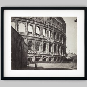May include: A black and white photograph of the Colosseum in Rome, Italy. The photo shows the exterior of the ancient amphitheatre, with its arches and columns.