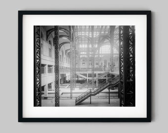 Könnte beinhalten: Schwarzweißfoto eines großen, offenen Industriegebäudes mit einem Metallgerüst und einer Treppe im Vordergrund.