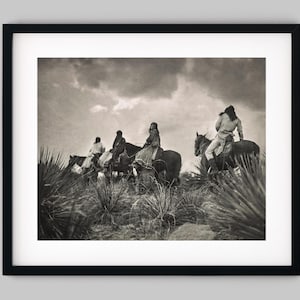 May include: Black and white framed print depicting a group of people on horseback traversing a landscape. The image is a sepia-toned photograph with a cloudy sky and desert vegetation in the foreground.