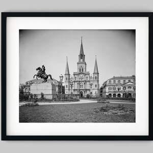 Puede incluir: Una fotografía en blanco y negro de una estatua de una persona a caballo frente a una gran catedral. La estatua está en primer plano y la catedral en el fondo. La foto está tomada desde un ángulo bajo, por lo que la catedral parece muy alta.
