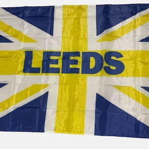 Puede incluir: Una bandera amarilla y azul con un diseño de Union Jack y la palabra "LEEDS" impresa en letras azules.