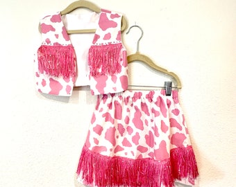 Pink and white cowhide print cowgirl costume with pink rhinestones and pink sequin fringe.