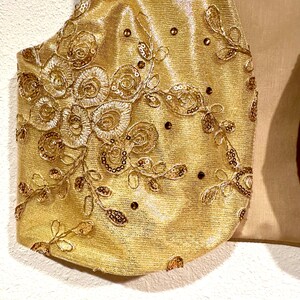 May include: Gold fabric with a floral design and sequins. The fabric has a shimmery finish.