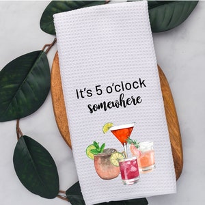 May include: White kitchen towel with the text "It's 5 o'clock somewhere" and a watercolor illustration of four different cocktails.