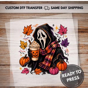 May include: A DTF transfer featuring a hooded figure with a white mask holding a coffee cup with a jack-o'-lantern face. The design includes a plaid scarf, orange and pink pumpkins, and colorful autumn leaves. Text reads CUSTOM DTF TRANSFER.