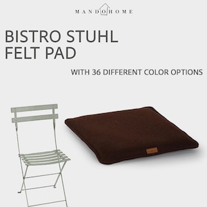May include: A dark brown square felt pad for a bistro chair, featuring a small rectangular brand label. The text MANDO HOME, BISTRO STUHL FELT PAD, and WITH 36 DIFFERENT COLOR OPTIONS appears above a light gray metal folding bistro chair.