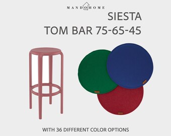 Puede incluir: Un taburete de bar rosa junto a tres cojines de asiento redondos en verde, azul y rojo. El texto MANDO HOME, SIESTA, TOM BAR 75-65-45 y WITH 36 DIFFERENT COLOR OPTIONS es visible. El taburete tiene cuatro patas y un reposapiés.