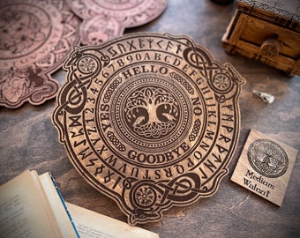 May include: A wooden Ouija board with a tree of life design in the center. The board has a circular shape and is surrounded by a Celtic knot border. The letters of the alphabet, numbers 1-9 and 0, and the words "yes", "no", "goodbye", and "hello" are engraved on the board. The board is made of medium walnut wood.