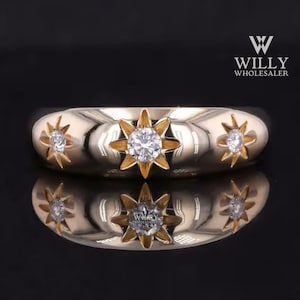 May include: A gold ring with three star-shaped settings, each with a small diamond in the center. The ring is on a black background.