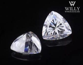 Puede incluir: Dos piedras preciosas triangulares transparentes con un diseño facetado. Las piedras preciosas están sobre un fondo negro.