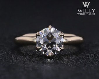 May include: A gold engagement ring with a large, round, clear diamond. The diamond is set in a prong setting and has a classic, elegant design.