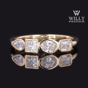 May include: A gold band ring with five clear diamonds. The diamonds are set in different shapes, including a pear, square, oval, and two baguette shapes.