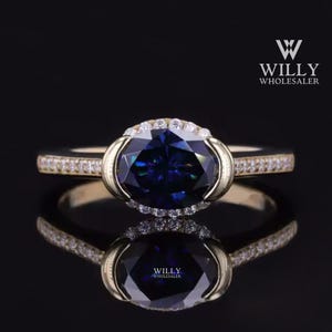 May include: A gold ring with a large oval-shaped blue gemstone surrounded by smaller diamonds. The ring has a delicate band with smaller diamonds.