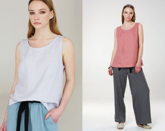 May include: Two women wearing sleeveless linen tops. The woman on the left is wearing a light blue top with a black belt and light blue pants. The woman on the right is wearing a pink top and gray pants.
