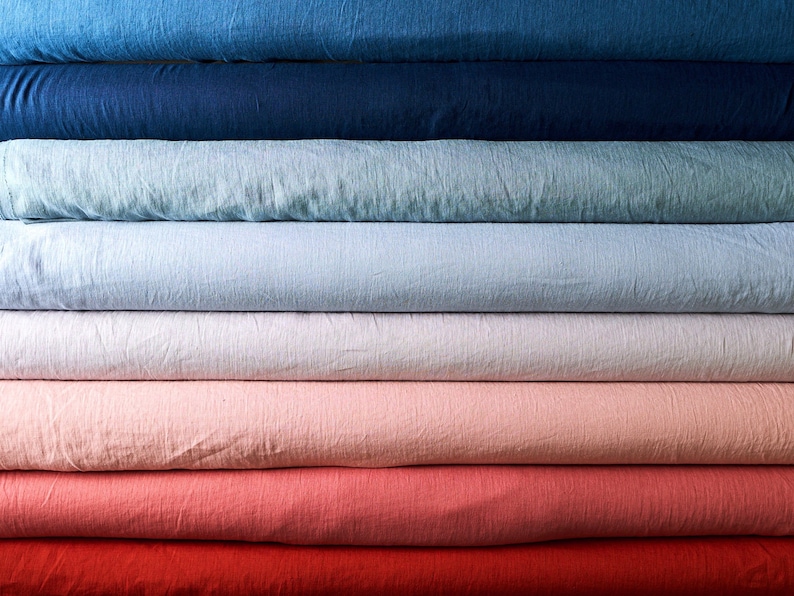 May include: A stack of fabric rolls in various shades of blue, light blue, white, pink, red, and orange. The fabric is a linen blend and has a textured surface.