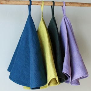 May include: Four linen tea towels hanging on a wooden rod. The towels are in shades of blue, green, yellow, and purple.