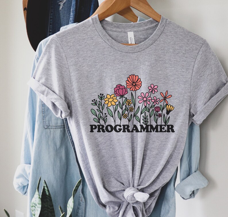 May include: A gray t-shirt with a graphic of colorful flowers and the word "PROGRAMMER" in black letters.